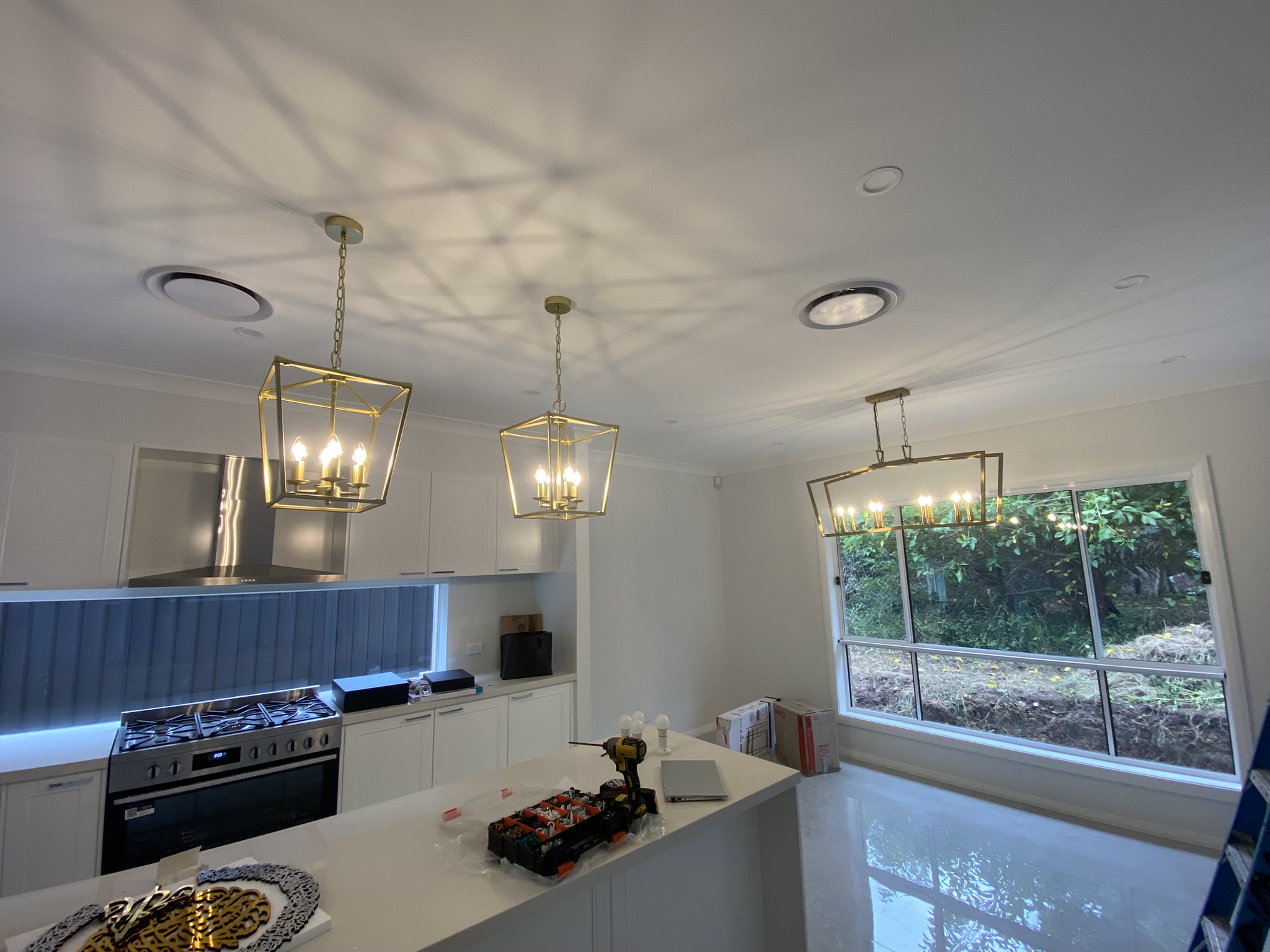 Brass pendant lights over a kitchen island and matching dining chandelier