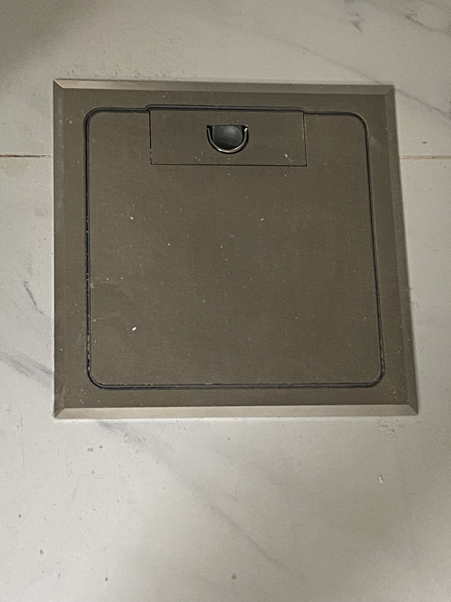 Recessed floor power point with brass hinged cover flush-mounted into tiled flooring