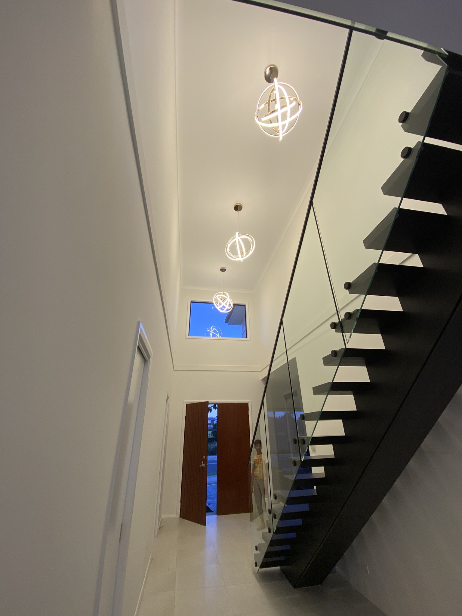 Three orbital ring pendant lights installed in a row along a hallway