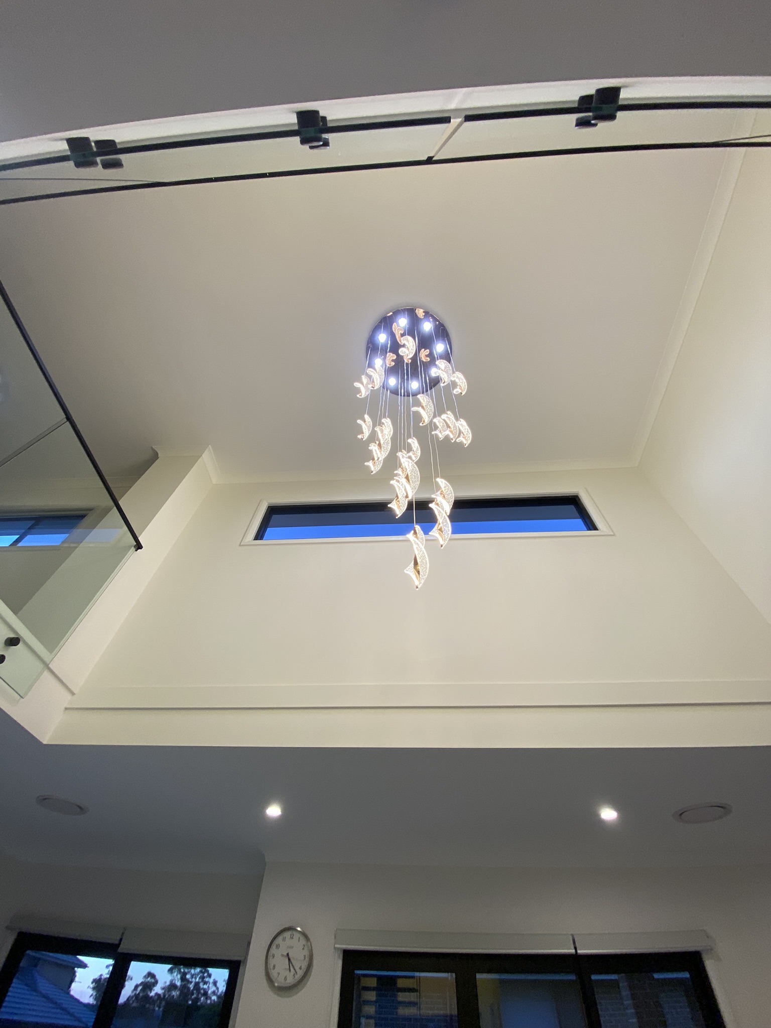 Spiral crystal chandelier with recessed downlights in a foyer void