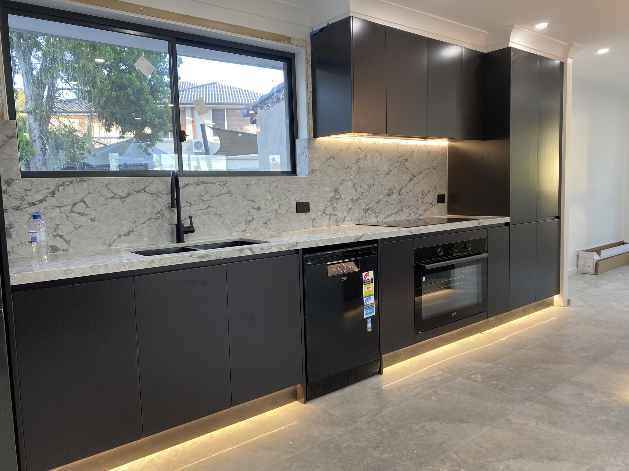 Kitchen splashback with matte black power points and concealed LED under-cabinet lighting