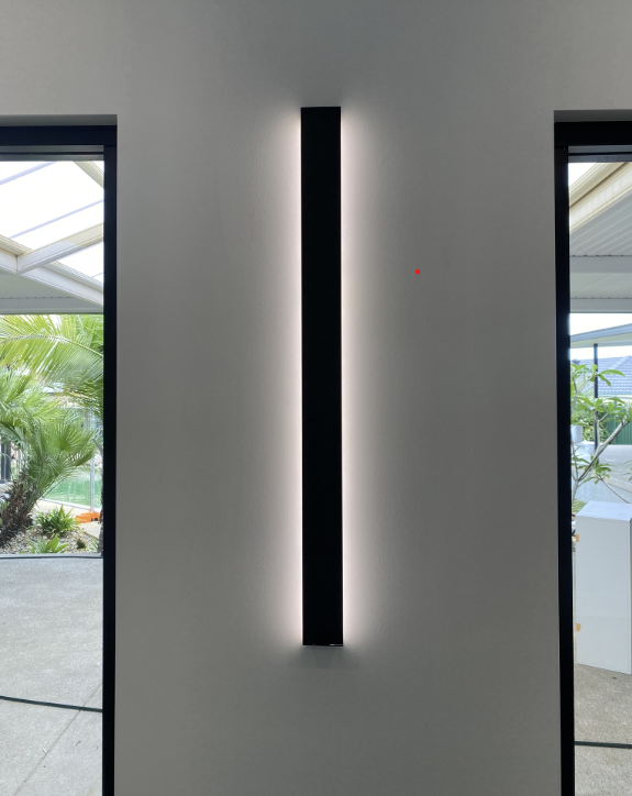 Matte black LED wall sconce installed between glass sliding doors with concealed wiring
